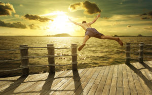 Man jumping off dock into water